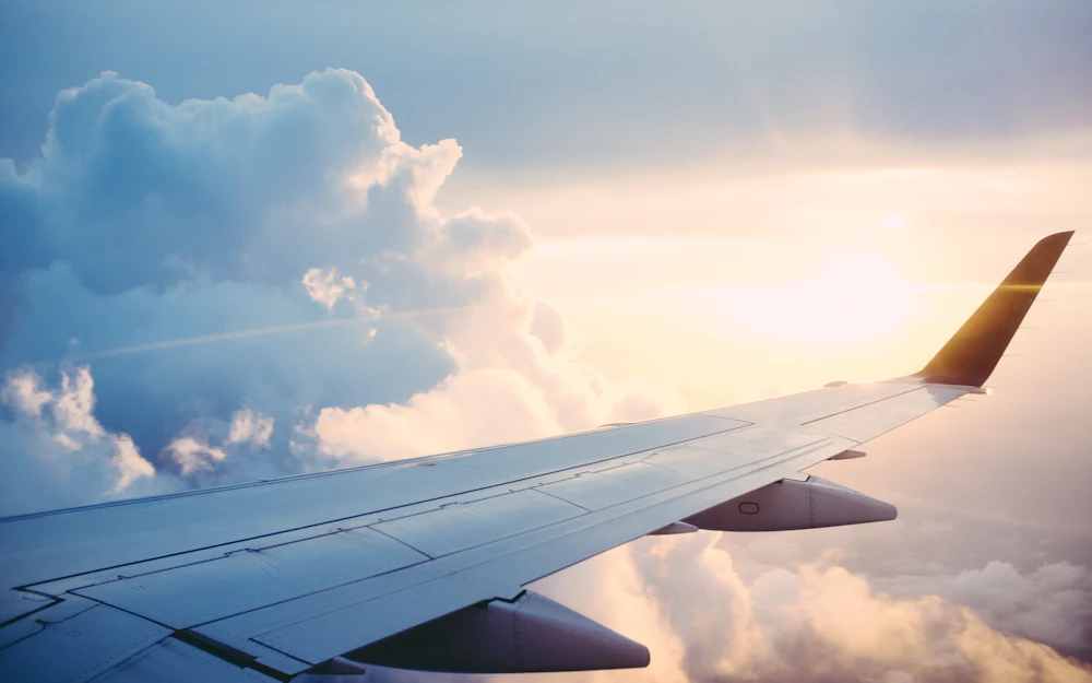 Ala de un avión sobre las nubes al atardecer